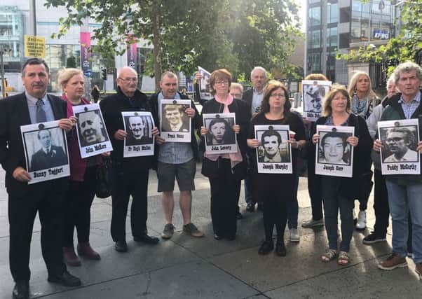 Families stand with photos of 10 people killed in disputed shootings in the Ballymurphy area of west Belfast in August 1971