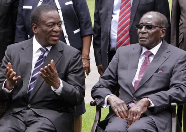 Emmerson Mnangagwa, left, then Vice President of Zimbabwe chats with Zimbabwean President Robert Mugabe in 2014. Mnangagwa later took over from Mugabe. The decimation of a beautiful country continues under his rule (AP Photo/Tsvangirayi Mukwazhi, File)