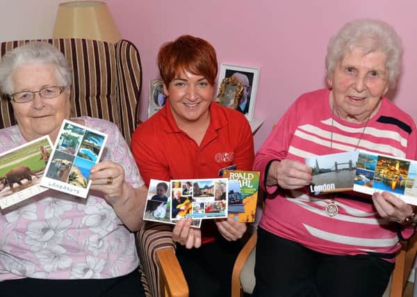Kathy Davison, centre, personal activities leader at Mahon Hall Care Home pictured with residents, Sybil McCoo, left, and Norah Mulholland and some of the postcards received from all over the World after an online appeal by Kathy. INPT42-200.