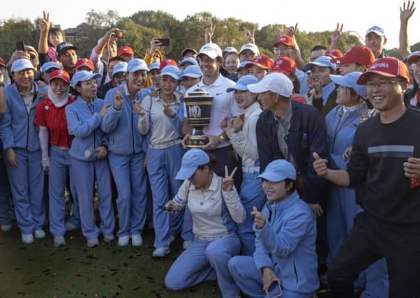 Rory McIlroy poses for photos with his trophy and the tournament workers after winning at Sheshan International Golf Club in Shanghai. Pic by AP.