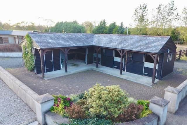 Features of the property include multiple stables and a floodlit sand arena