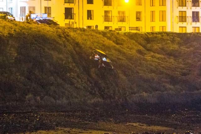 A car hangs onto the verge after going over the cliff in Portballintrae on Monday night - pic by McAuley Multimedia