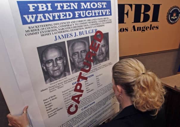 FBI Special Agent Mary Prang sets up a 'wanted' poster overstamped 'captured' for James 'Whitey' Bulger, before a news conference at FBI headquarters in Los Angeles Thursday, June 23, 2011