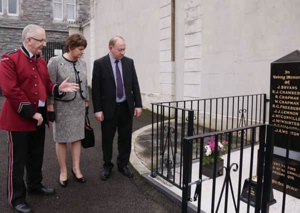 First Minister Arlene Foster with MLAs Danny Kennedy (left) and William Irwin study a memorial to the Kingsmills victims