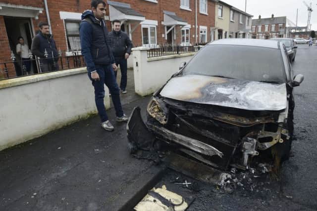 Daniel Cirpaci looks at the damage cause to his car after it was set alight in the Ebor Street area of Belfast on Tuesday morning