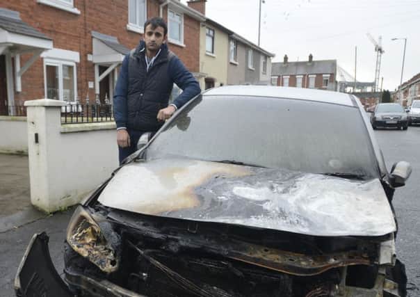 Daniel Cirpaci looks at the damage cause to his car after it was set alight in the Ebor Street area of Belfast on Tuesday morning