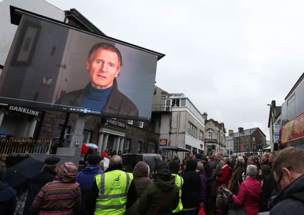 Spectators at the rally watch Liam Neeson's video message on a big screen