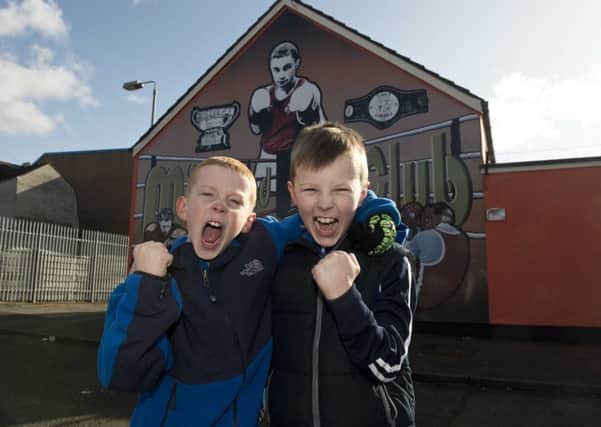 Ryan McDonald and Tony Watson celebrate Carl Frampton's win against Scott Quigg in front of a mural of the boxer in Tigers Bay, Belfast