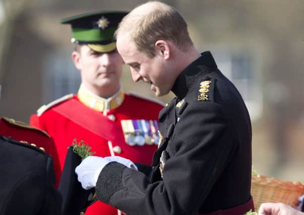 The Duke of Cambridge attaches a sprig of shamrock to his hat as he presents the Irish Guards with shamrocks