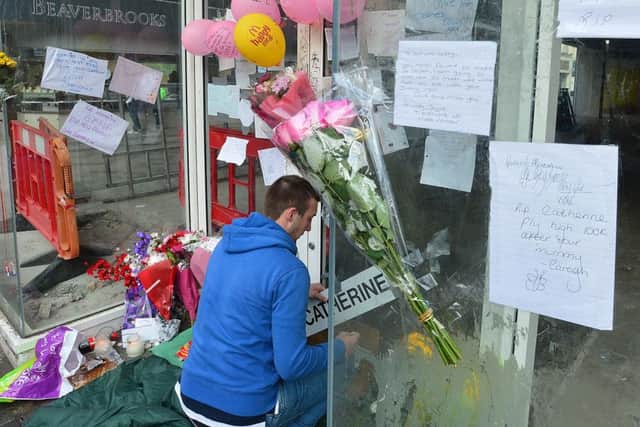 A man tends the floral tributes to Catherine Kenny in Belfast city centre