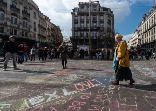 After the Brussels terror attacks, a man walks by solidarity messages written in chalk outside the stock exchange in the city on Tuesday, March 22, 2016. (AP Photo/Geert Vanden Wijngaert)