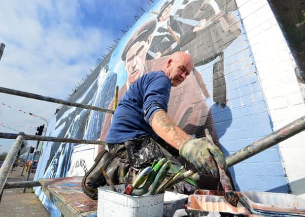 A west Belfast mural to mark the 100th anniversary of the Easter Rising which features unionist leader Edward Carson had paint thrown over it just hours after it was completed. The mural was painted on the International Wall on the Falls Road as part of a display to mark the rising's centenary this weekend. Marty Lyons pictured restoring the mural on Wednesday March 23.