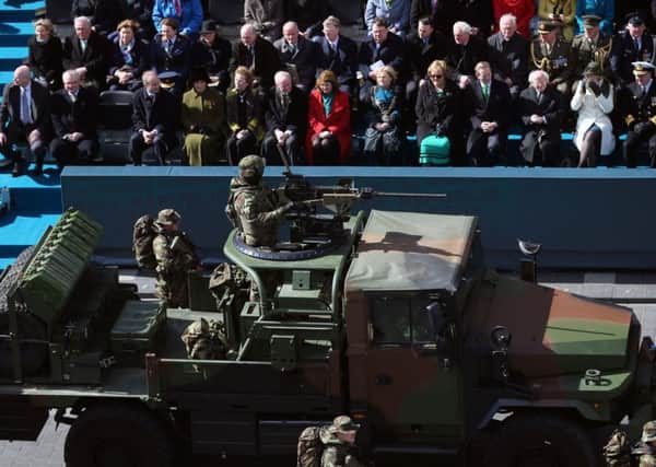 Dignitaries including Martin McGuinness, middle of front row, and ex Irish presidents Mary Robinson, left of him, and Mary McAleese, far left, as a military vehicle passes in the Easter Rising commemorations in Dublin. Photo: Niall Carson/PA Wire