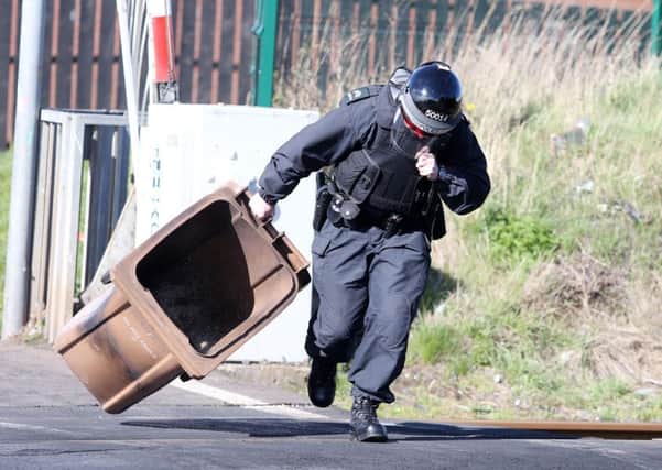 A PSNI officer removes a bin from the train tracks during disturbances in Lurgan. Picture: Jonathan Porter/PressEye