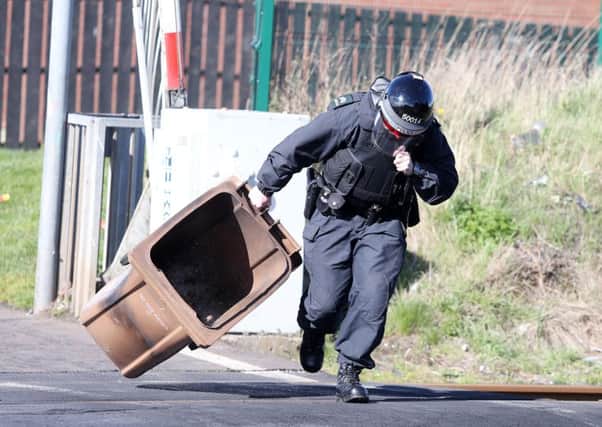 A police officer is pictured moving a wheelie bin from around the area of the train line in Lurgan on Monday, March 28