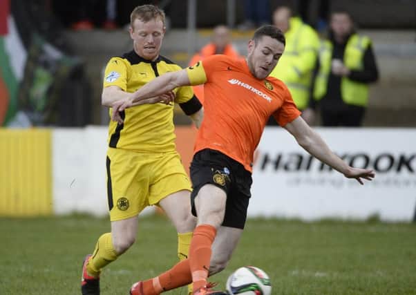 Carrick's Aaron Harmon  in action with Cliftonville's George McMullan