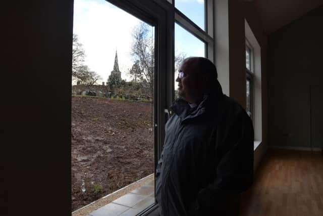 Rev Willie Nixon looks out of the damaged new Hall at Drumbeg Church, which can be seen in the background