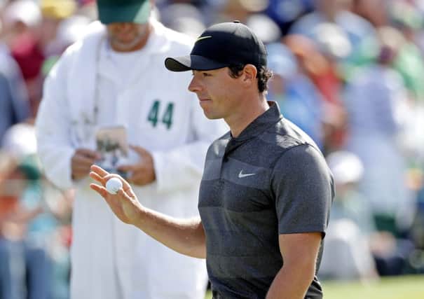 Rory McIlroyholds up his ball after putting out on the ninth hole