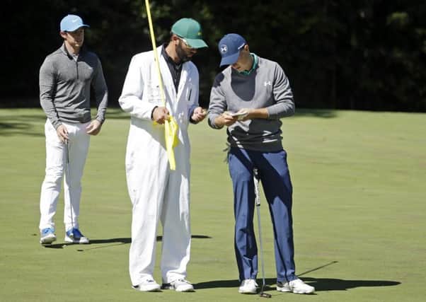 Rory McIlroy stands by as Jordan Spieth checks his course notes