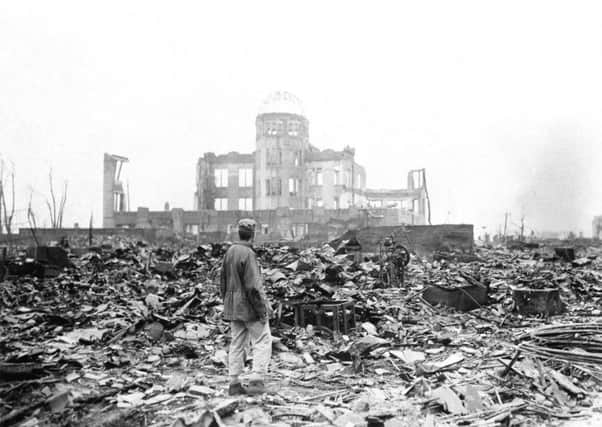 An allied correspondent stands in the rubble in front of the shell of a building that once was a exhibition centre and government office (now the Atomic bomb dome)  in Hiroshima, Japan, a month after the first atomic bomb used in warfare was dropped by the US on Aug 6, 1945. (AP Photo/Stanley Troutman, File)