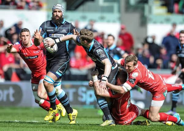 Glasgow Warriors' Finn Russell offloads despite the tackle of Scarlets' Hadleigh Parkes