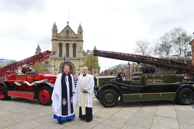 Dean John Mann and Father Michael Sheehan in front of St Anne's yesterday with fire engines from Dundalk and Drogheda that helped Belfast in 1941
