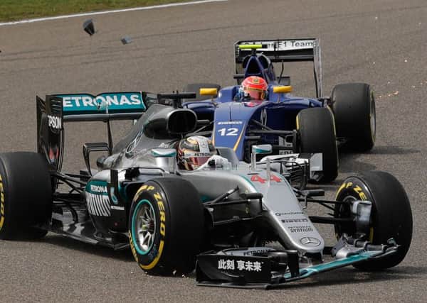 Debris flies from the front wing of the car of Lewis Hamilton