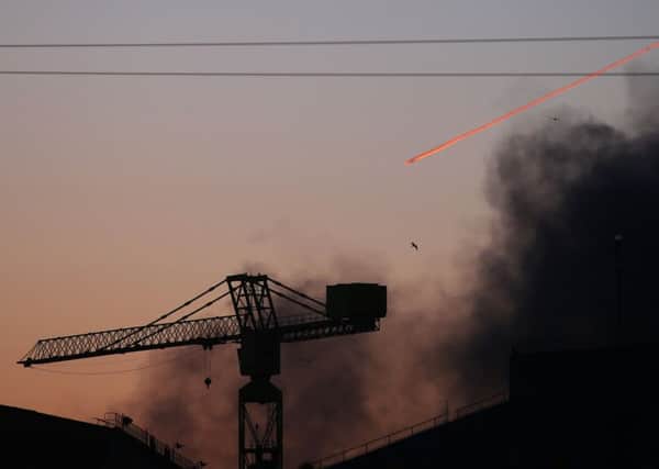 Smoke in this photo can be seen drifting across the sky from the vantage point of the citys shipyard in east Belfast as a plane flies above.