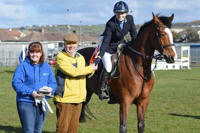 Jenny McNeill, from RUAS, and CCCS director Bill Roulston MBE, presenting Tegan White on Lenamore Lux with winners rosette in the 1.30m class at Portrush