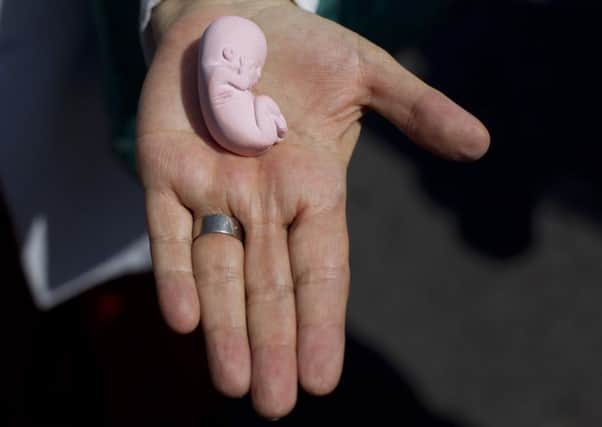 An anti-abortion activist shows a plastic doll depicting a foetus
