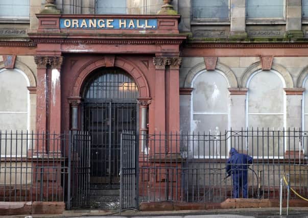 Contractors power hose the front of Clifton Street Orange Hall in North Belfast after another paint bomb attack.