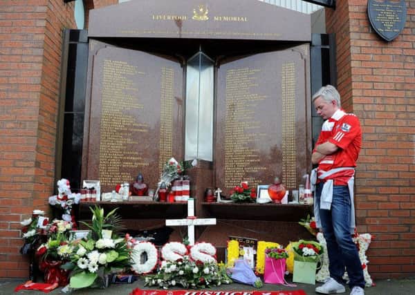 File photo dated 30/03/14 of a Liverpool fan looking at tributes at the Hillsborough memorial at Anfield, Liverpool. Ninety-six Liverpool supporters died in the Hillsborough disaster due to crushing following the admission of a large number of fans through exit gates, a jury has found. 
PRESS ASSOCIATION Photo.. Martin Rickett/PA Wire