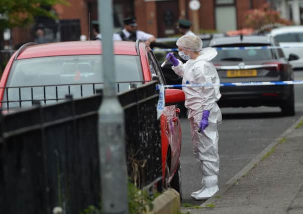 Police forensics attend the aftermath of the shooting in west Belfast