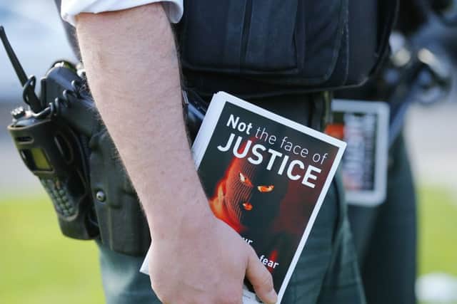 Police officers hand out leaflets at a protest rally against recent murders, attempted murders and maimings held in west Belfast