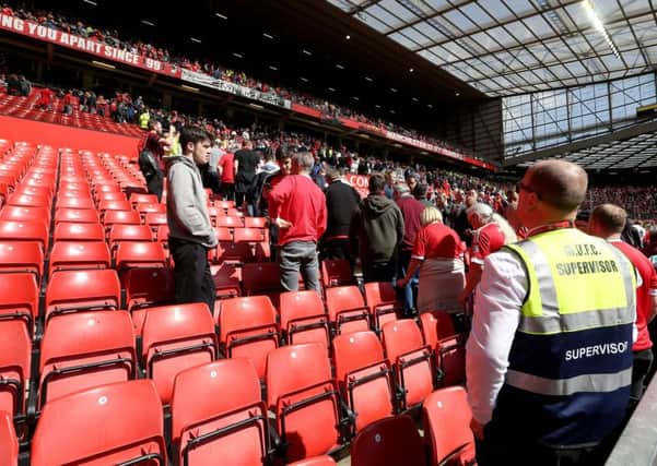 Fans leave the stands after a security announcement during the Barclays Premier League match at Old Trafford, Manchester