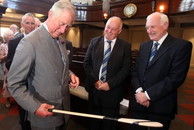 The Prince of Wales holds a hurley presented to him by members of the local GAA club during a visit to the Portico Arts Centre in Portaferry