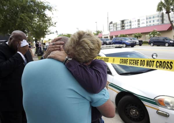 Terry DeCarlo, executive director of the LGBT Center of Central Florida, center, is comforted by Orlando City Commissioner Patty Sheehan, right, after the murder of 50 people at a nightclub in Orlando