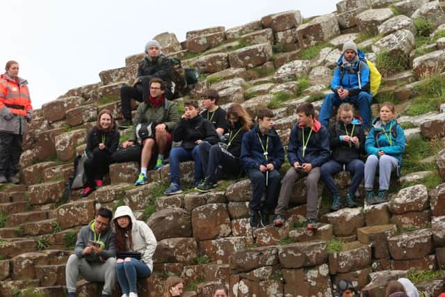 Tourists await the arrival of the Queen Elizabeth II and the Duke of Edinburgh to the Giant's Causeway on the Co Antrim coast during the second day of her visit to Northern Ireland to mark her 90th birthday