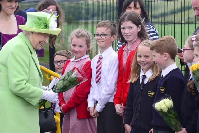 Pupils from local schools present the monarch with flowers during her visit to Coleraine train station