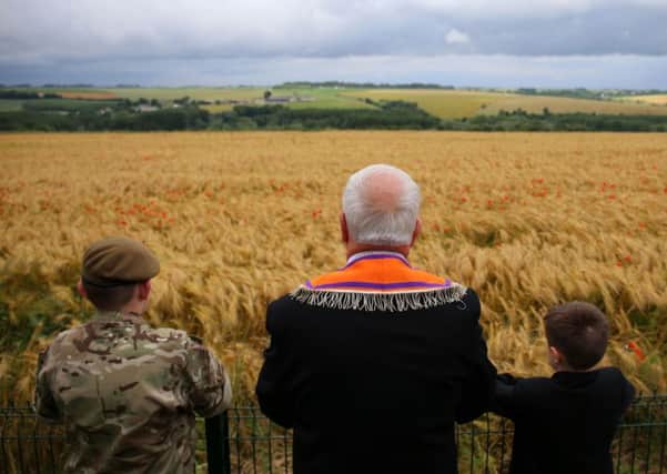 Former RUC officer Cecil Haire from Co Fermanagh and his grand children Aaron (left) and Calib (right) look down across a sloping poppy field near the Ulster Memorial Tower at Thiepval, France, on Friday, when a ceremony to mark the centenary of the Battle of the Somme was  held. Photo: Niall Carson/PA Wire
