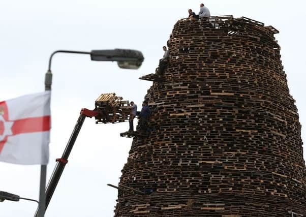 Men construct a bonfire in the Ballymacash area of Lisburn, as building continues on huge loyalist bonfires, which are traditionally lit on the "Eleventh night" to usher in the Twelfth commemorations
