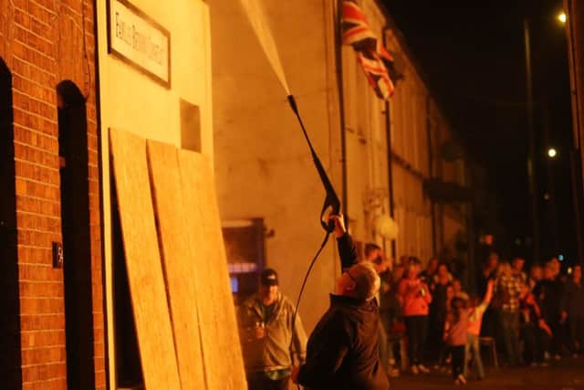 A man dampens down a building as a bonfire is lit on the Shankill Road in Belfast on the "Eleventh night" to usher in the Twelfth commemorations