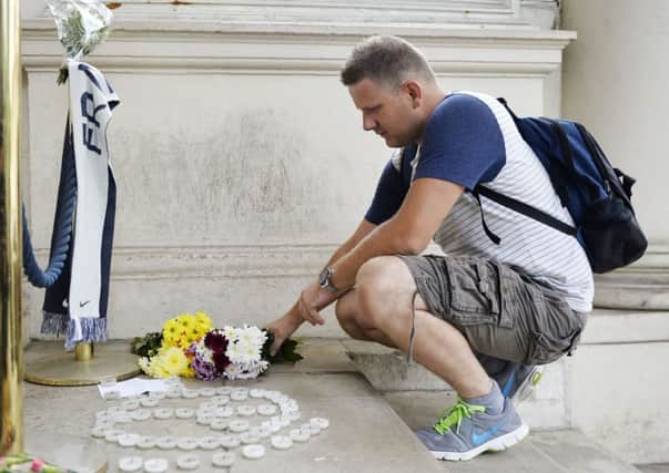 A man lays flowers outside the French Embassy in London following the attack in Nice