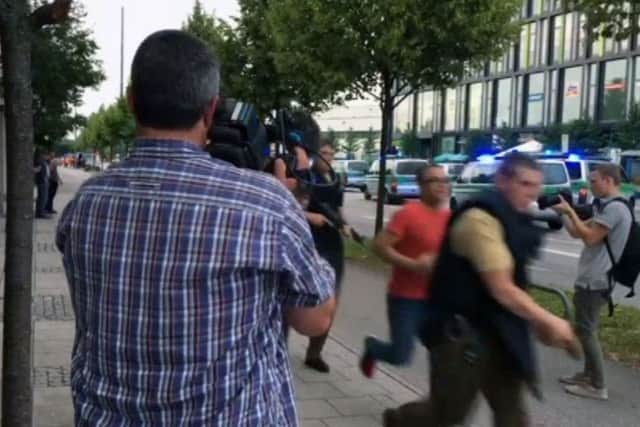 Armed police move past onlooking media responding to a shooting at a shopping center in Munich, Germany, Friday July 22, 2016.   (AP Photo/APTV)