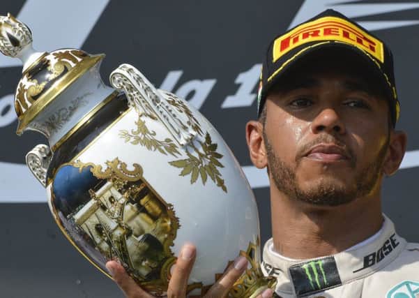 British Formula One driver Lewis Hamilton celebrates with the trophy on the podium after winning the Formula One Hungarian Grand in Mogyorod, north-east of Budapest, Hungary