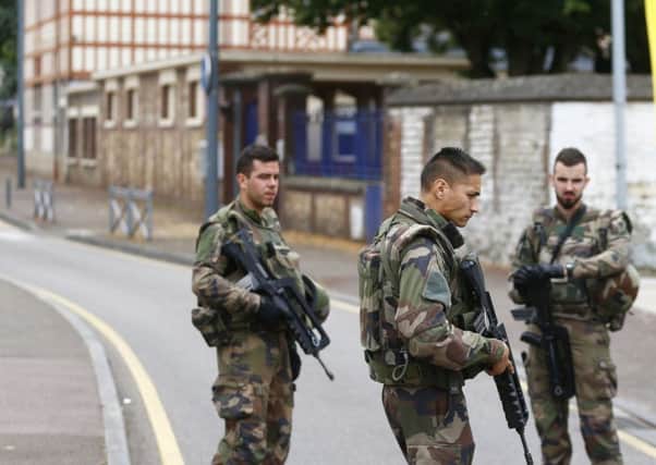 French soldiers stand guard as they prevent  the access to the scene of an attack in Saint Etienne du Rouvray, Normandy, France, Tuesday, July 26, 2016. Two attackers invaded a church Tuesday during morning Mass near the Normandy city of Rouen, killing an 84-year-old priest by slitting his throat and taking hostages before being shot and killed by police, French officials said. (AP Photo/Francois Mori)