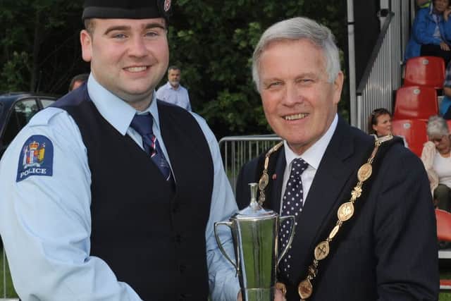 Pipe Major Emmett Conwayof the New Zealand Police Pipe Band receives the Grade 1 prize from the Chieftain of the Gathering Councillor Brian Bloomfield, Mayor of Lisburn & Castlereagh City Council