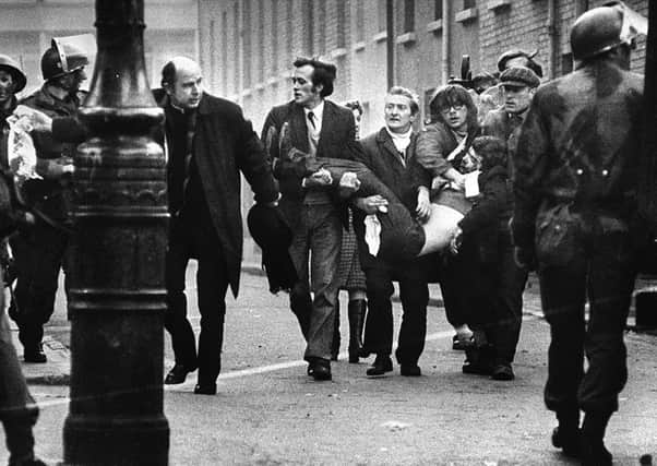 Bishop Daly, clutching a blood-soaked handkerchief, helps clear a path for injured protester Jackie Duddy during Bloody Sunday in Londonderry in 1972