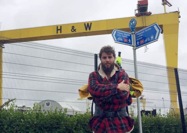 Alex Ellis-Roswell poses beside one of Harland & Wolffs iconic cranes before he left for Scotland to resume his epic journey