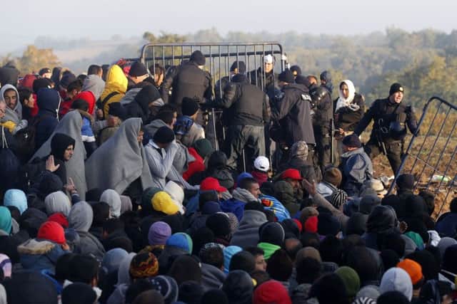 Migrants gather around Croatian police officers guarding a border between Serbia and Croatia, near the village of Babska, Croatia, late last year. Croatia, which has erected relatively few shelters along its borders with Serbia and Slovenia, directed thousands into special trains and bus convoys Tuesday to Slovenia. (AP Photo/Darko Vojinovic)